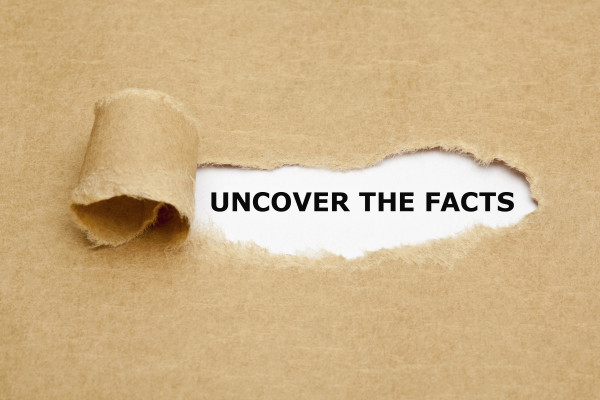 a piece of torn paper revealing the words," Uncover the facts"