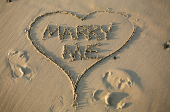 Romantic proposal - Marry me written in a heart in the sand on a beach