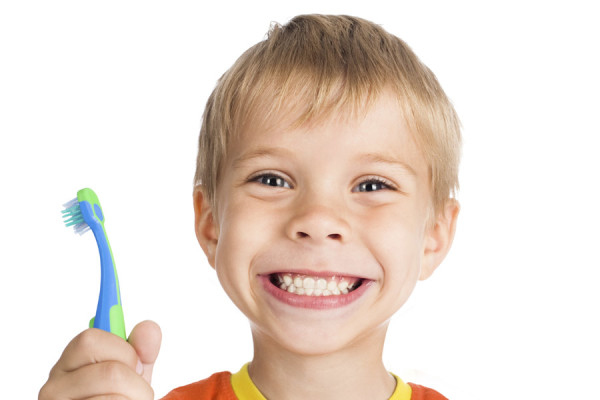picture of a broad smiling youth holding his toothbrush in his hand