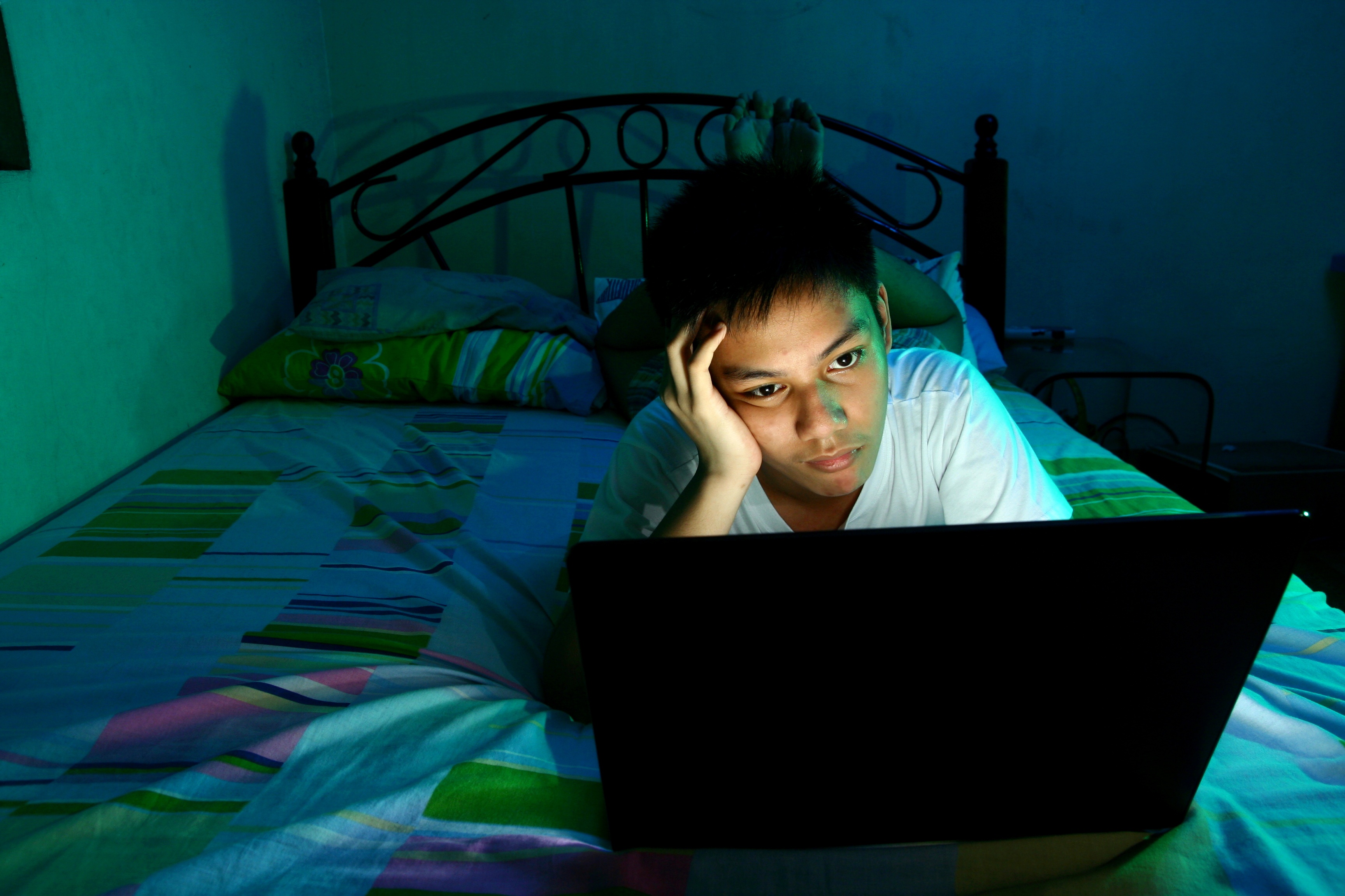 Young Teen in front of a laptop computer and on a bed