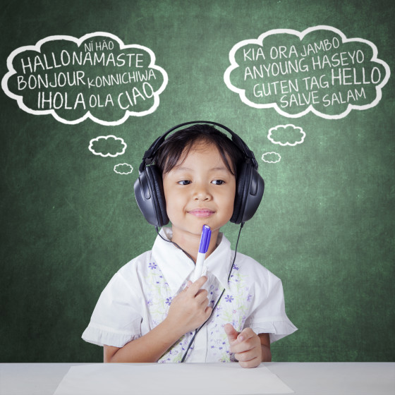 Lovely female elementary school student using headphones to study multi language by listening, shot in the class