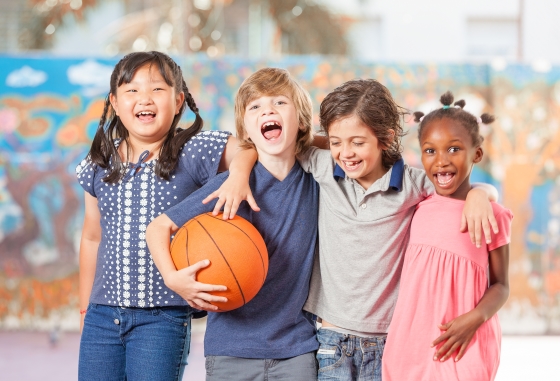 making sure your kids stay healthy at school - four happy elementary school kids playing basketball