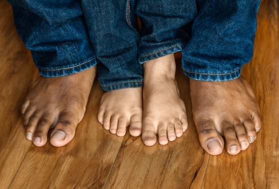 better toenails for men - feet of stepdad and stepson standing on wooden floor