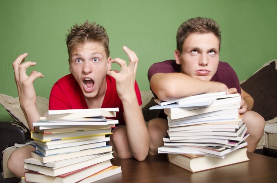 does more homework equal a better education? - two students - one overwhelmed and one surrended to the piles of homework in front of them