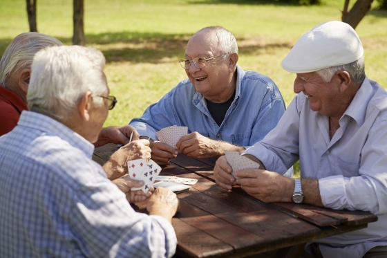 slowing down dementia in aging men - a group of senior men enjoying a game of cards in the park