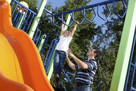 stepfather and son playing on monkey bars at the park