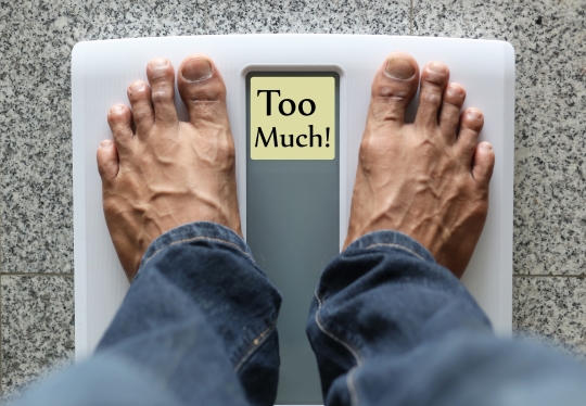 weight loss tips for men - Man standing on weight scale with text: Too much