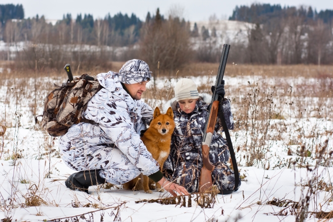 kids learning to hunt - stepdad shows his son traces of animals on the snowy field