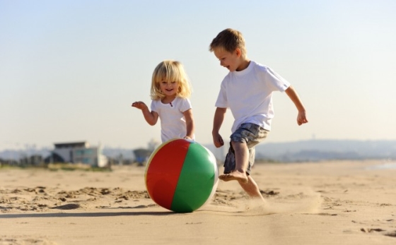 outdoor activities to help your kids develop motor skills - a brother and sister playing with a beach ball on the beach