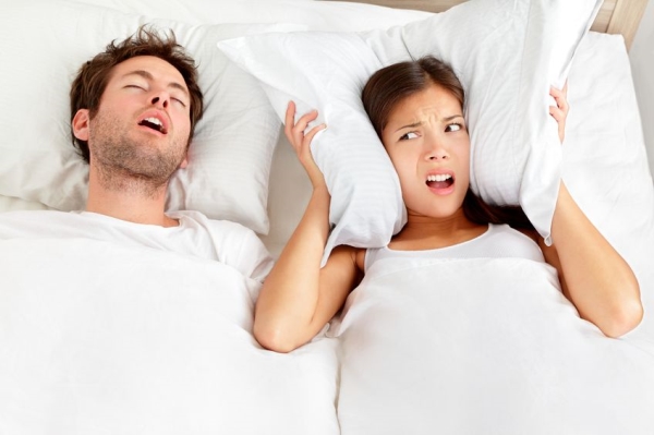 Snoring man Couple in bed, man snoring and woman can not sleep, covering ears with pillow for snore noise Young interracial couple, Asian woman, Caucasian man sleeping in bed at home