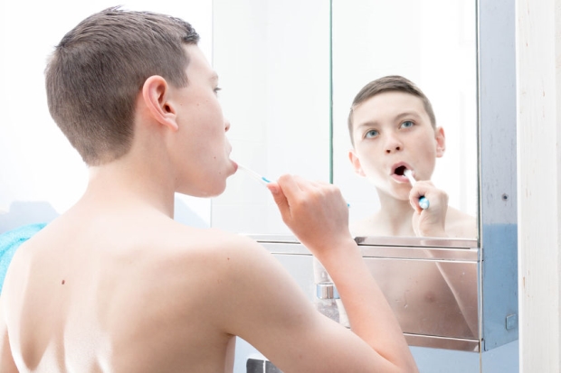 your teen and their hygiene - teenage boy brushing his teeth