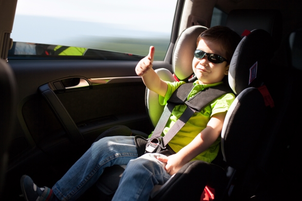 car seat check - toddler sitting in car seat giving thumbs up