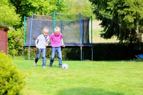 make your backyard safe for play - Two happy brothers playing soccer in the garden