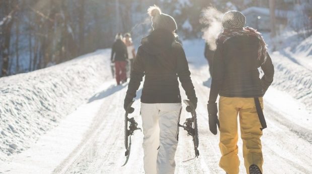 avoiding common winter sports injuries - two snowboarders trudging up the hill