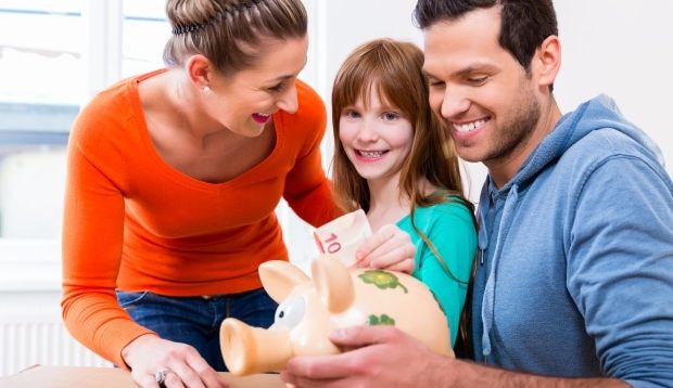 showing kids how to save - mom and stepdad encouraging daughter to use piggy bank