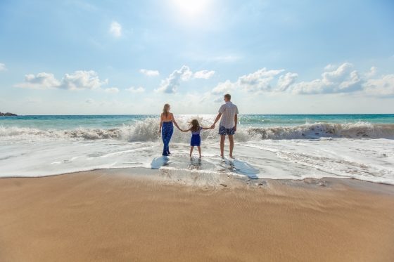 vacation ideas for the entire family - picture of family (man, woman and child) walking on the beach