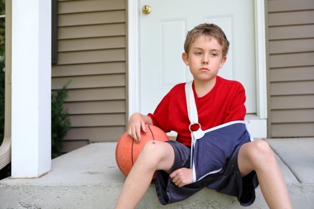 helping your teen recover from a sports injury - young boy with arm in sling with a basketball