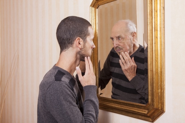 Growing older-young man looking at an older himself in the mirror