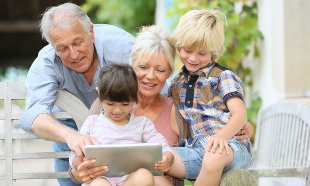 help your grandparents enjoy their golden years - Grandparents playing with grandkids on a tablet