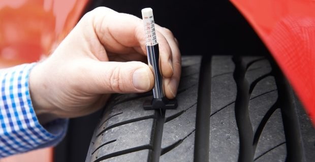 using tire gauge to check remaining tire tread