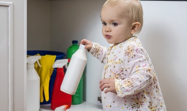hidden dangers in regular everyday things -Little girl playing with household cleaners