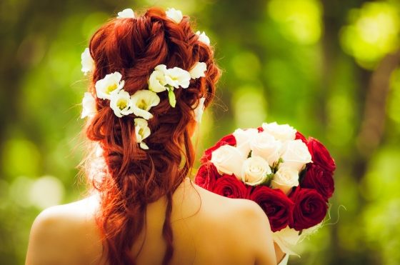 making the most of your wedding decorations - bride with hair decorated with roses and holding a bouquet of roses