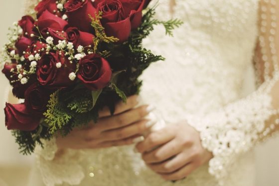 bride holding wedding bouquet of red roses