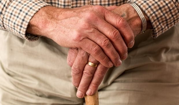 hands of elderly person on cane