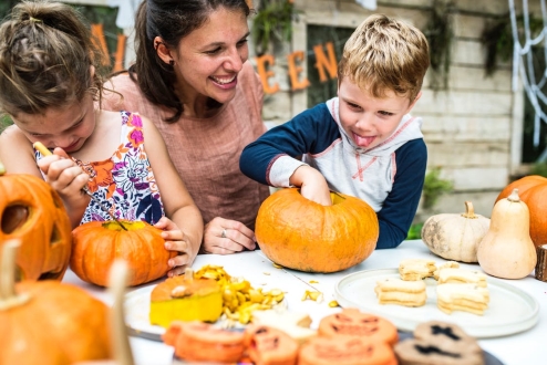 mom supervising kids carving pumpkins