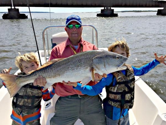 life lessons fishing can teach kids- a man and his kids holding a big fish
