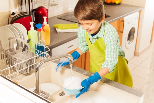 chores to help mature your kids-young boy washing dishes
