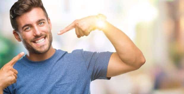 ways to naturally whiten your teeth-a smiling man pointing at his teeth