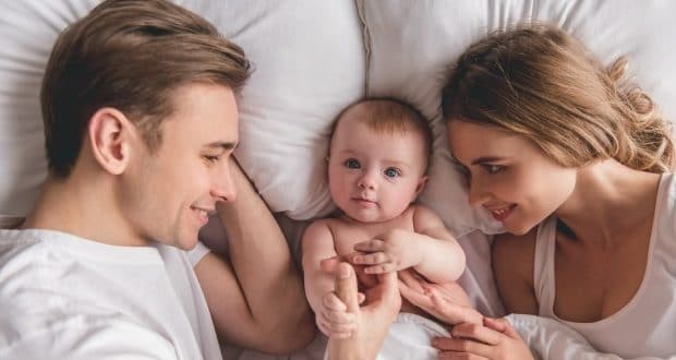 tips to keep your newborn safe-a couple lying on a bed with their newborn
