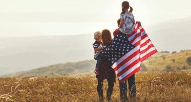 places to raise a family in the US-a family on a field holding the US flag