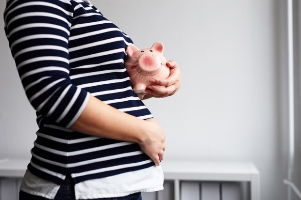 Ways to save money-a pregnant woman holding a piggy bank