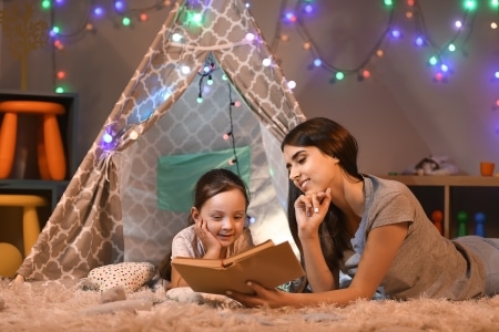 lighting ideas for your kids room-a mom and daughter reading a book over some fairy lights