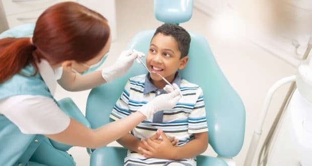 Reasons why dental visits are important for kids-a boy getting his teeth examined by a dentist