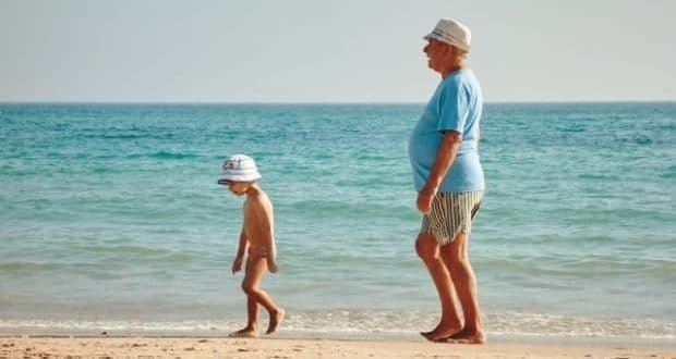 ways grandparents can help with their grand-kids-a grandpa taking a stroll with grandson on a beach