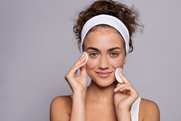 skincare routine for a teenager-a teen holding cotton pads to her flawless skin