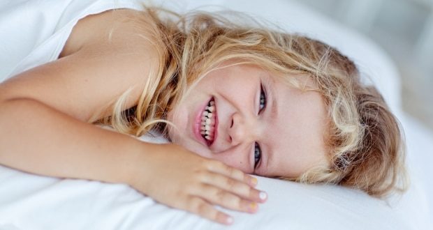 Tips to get excited kids to sleep- Happy girl on the bed
