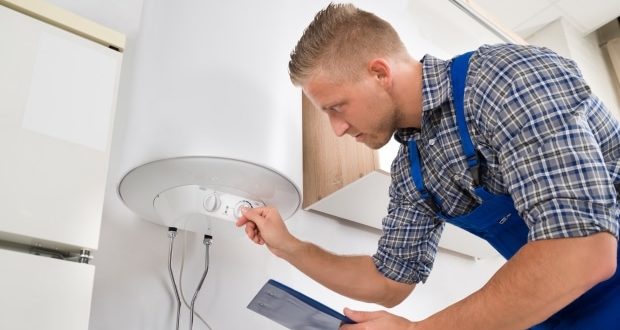 How to adjust the temperature of a water heater- A man adjusting the temperature of a water heater