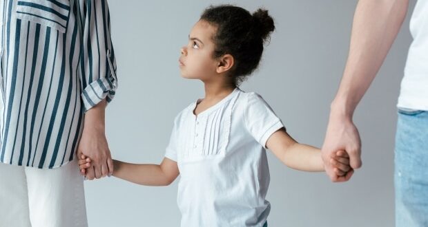 Tips for handling visitation arrangement after a divorce - A little girl holding the hands of her parents