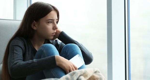 How to help your teen handle anxiety - Anxious teen girl looking out of the window