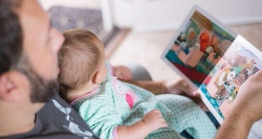 Stepdad reading out loud with baby on lap