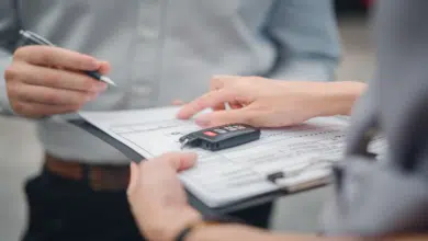 Customer with car dealer agent making deal, sign on agreement document contract in office