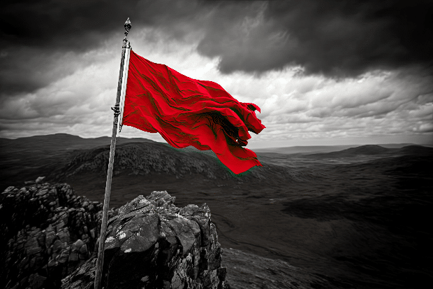 red flag blowing in the wind atop craggy peak, with view of the surrounding landscape