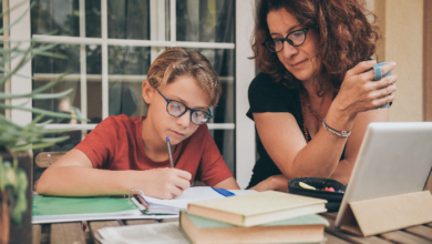 Homeschooling decision for families-Young student doing homework at home with school books newspaper, digital pad helped by his mother.