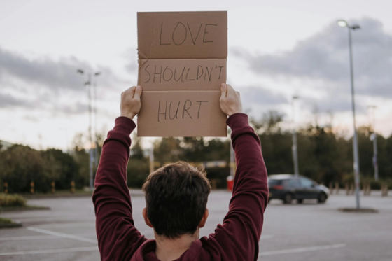 Child holding sign, "Love Shouldn't Hurt"