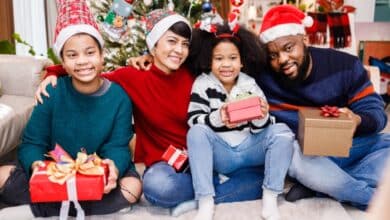 Building New Traditions In A Blended Family: A Stepfather’s Guide To Navigating Christmas-Happy blended family of four bonding sitting on the floor together with Christmas decorations in the living room.