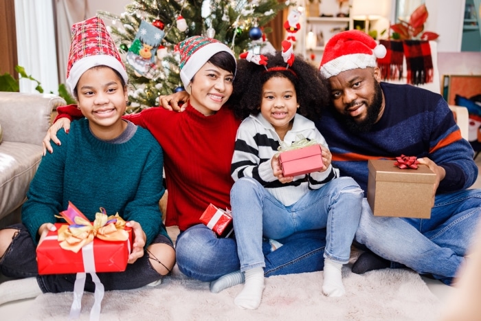 Building New Traditions In A Blended Family: A Stepfather’s Guide To Navigating Christmas-Happy blended family of four bonding sitting on the floor together with Christmas decorations in the living room.